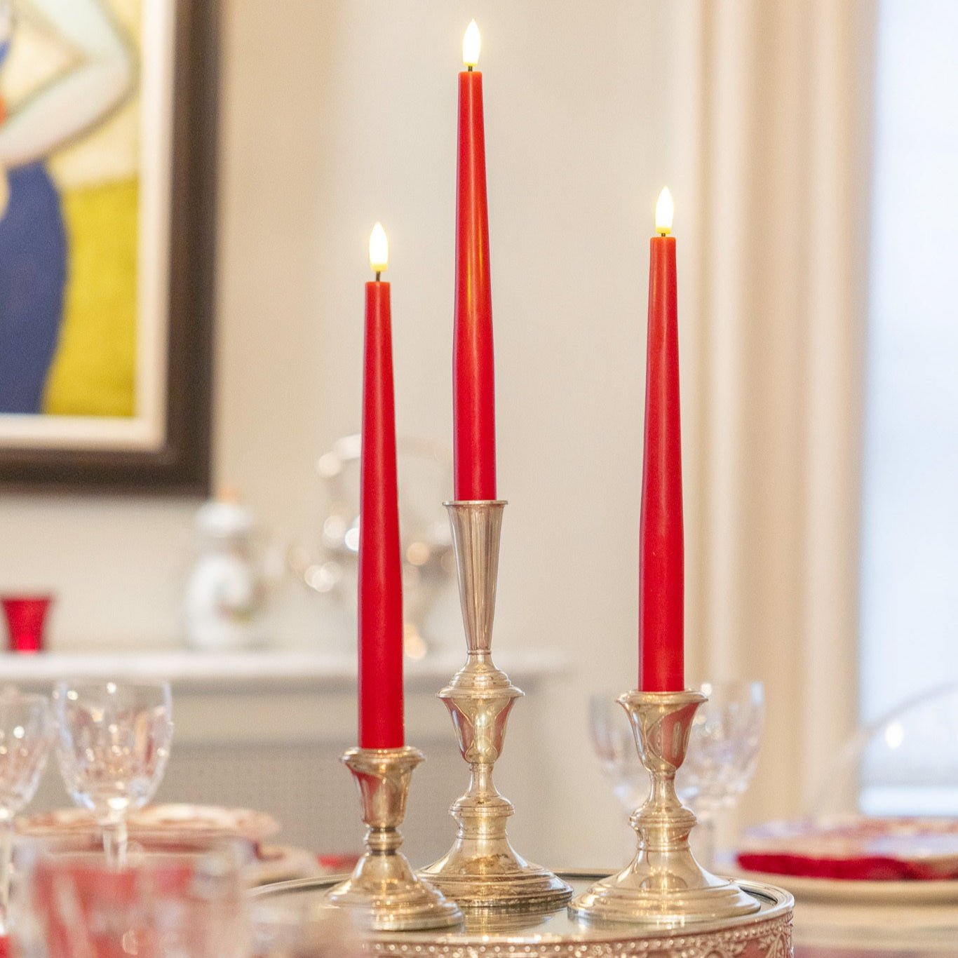 Flameless wax taper candles glowing in polished candlesticks on a set holiday dinner table