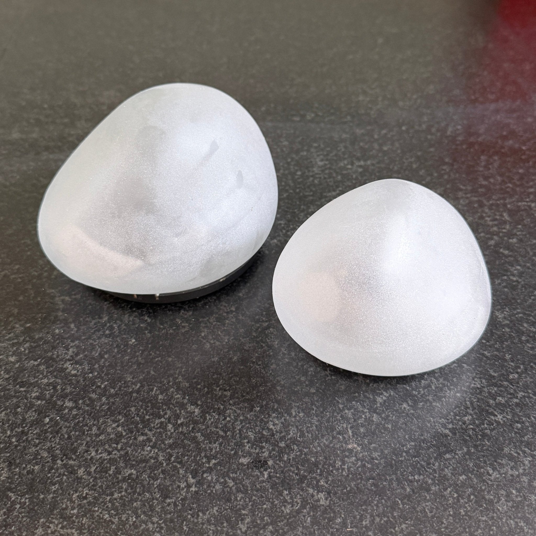 Two frosted solar stone lights side by side showing the medium and large sizes